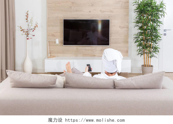 坐在沙发上的妇女, 头上戴着毛巾看电视